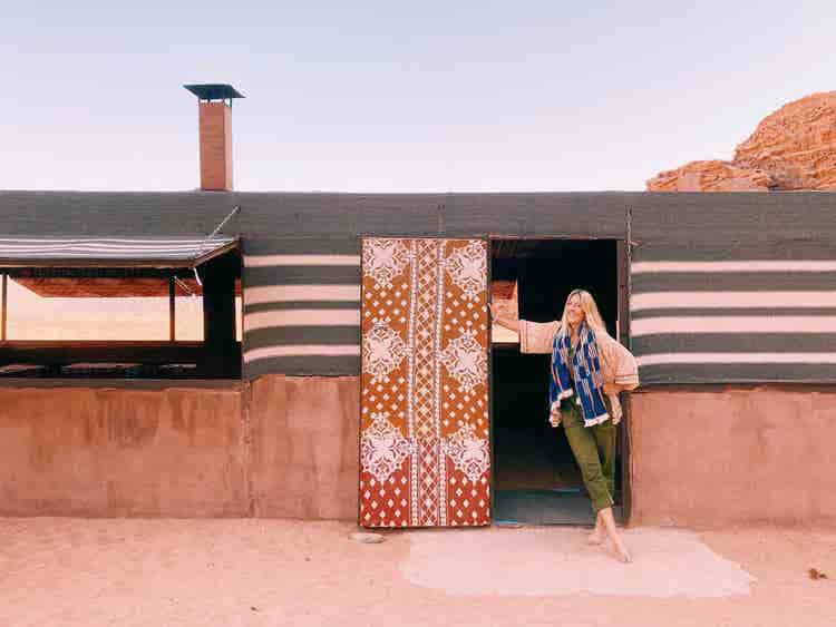 Digital nomad Frankie Ratford stands out the front of a luxe international location.