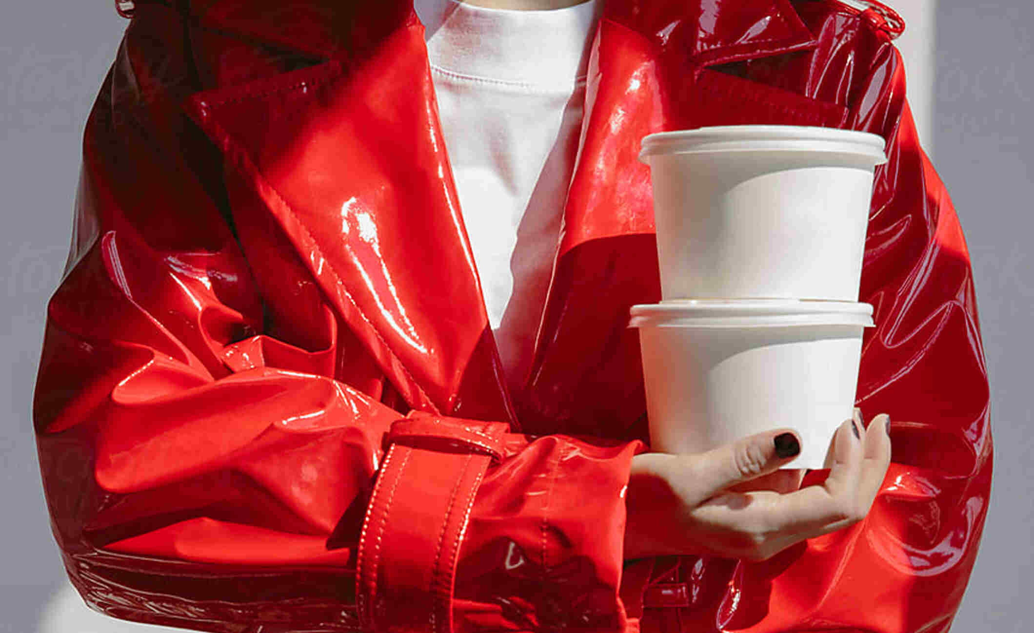 Person in red pleather coat holds two white takeaway containers